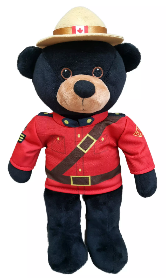 Plush bear wearing a red Mountie uniform and hat with a Canadian flag on a white background